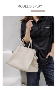 Macro view of minimalist beige leather tote bag featuring durable handles and metal buckles
