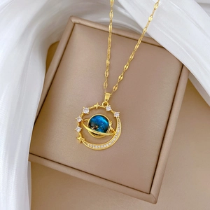Detail of a gold planet necklace with blue stone and sparkling zircons on silk background