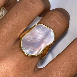Irregular white shell gold ring with minimalist geometric design worn on a finger