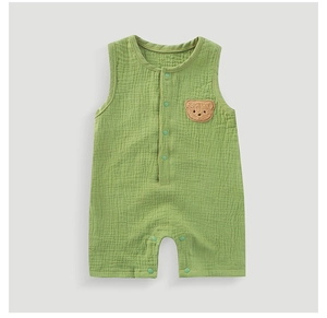 Detail of baby muslin romper with breathable green cotton fabric and bear patch