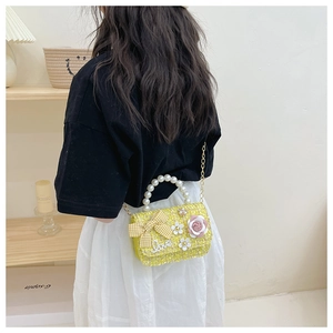 Detail of yellow tweed kids handbag featuring a pearl handle and chic bow decoration