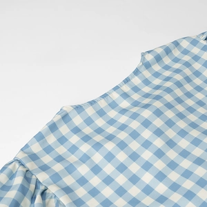 Close-up of blue and white gingham fabric with ruffle edge and detailed stitching