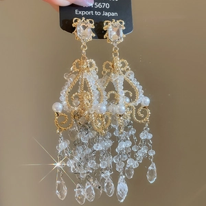 Detailed macro view of long gold tassel earrings with crystal beads and white pearls