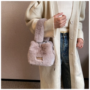 Close-up of pink faux fur bucket bag with metal ring handle and silver brand plaque
