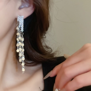 Detailed view of silver long fringe tassel earrings worn on ear with zircon sparkles
