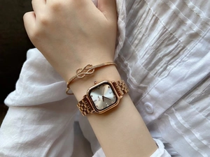 Detail of rose gold square watch and sparkling infinity knot bracelet on female wrist