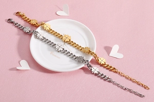Detailed view of gold and silver clover bracelets on a white ceramic plate decoration