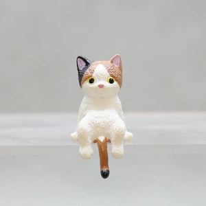Macro shot of a cute calico cat figurine ornament sitting on a desktop edge decoration