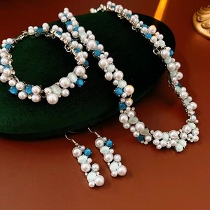 Dettaglio di un set di gioielli vintage con perle e strass su cuscino di velluto