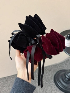 Detail view of large velvet bow hair clips in black and wine red with sparkling glitter