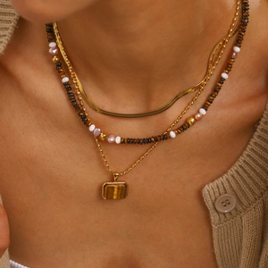 Layered gold stainless steel necklace with tiger eye stone and pearls on a model