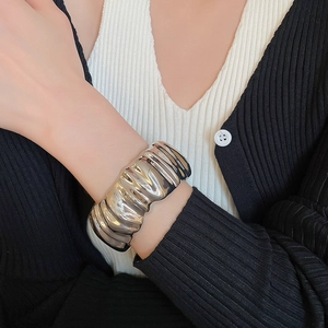 Détail d'un large bracelet manchette en métal argenté avec motif froissé texturé