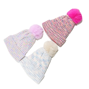 Close-up of cable knit texture and faux fur pom-pom on colorful winter beanies