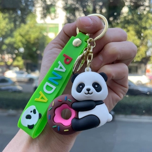 Detail of cute panda keychain with donut and green silicone strap with PANDA lettering