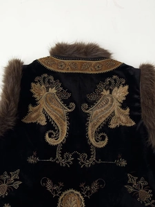 Close-up of intricate gold bead embroidery and plush fur trim on black velvet vest