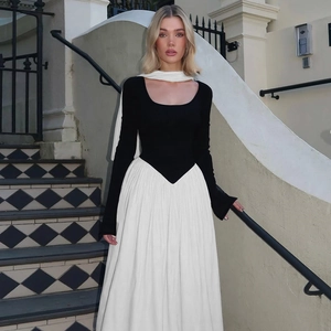 Detail of elegant black long sleeve bodice joined with white pleated maxi dress skirt