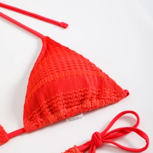 Dettaglio del top bikini arancione con trama 3D intrecciata e laccetti sottili