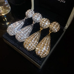 Macro shot of gold and silver teardrop earrings with pavé crystals in luxury jewelry box
