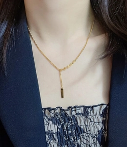 Close-up of a minimalist 18K gold plated bar pendant necklace on a female model