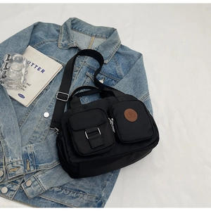 Detail der schwarzen Nylon-Umhängetasche mit Multi-Taschen-Design auf Jeansjacke