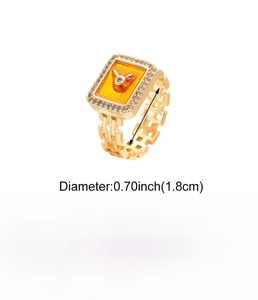 Detail view of gold watch-style ring with orange enamel dial and copper chain band