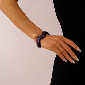 Macro shot of wavy thick acrylic resin bangle in deep purple with glossy finish