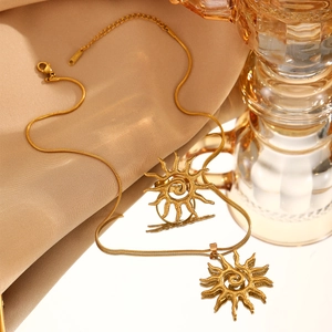 Detail of golden sun pendant with spiral design on sleek snake chain necklace