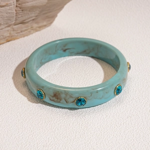 Detail of light blue marble resin bangle featuring embedded dark blue rhinestones