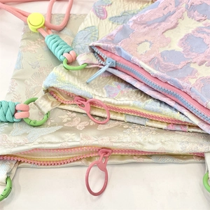 Detail view of colorful jacquard fabric crossbody bags with woven rope straps and zippers