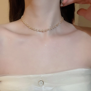 Close-up of minimalist gold fringe zircon necklace worn by a model on the collarbone