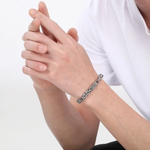 Gros plan d'un bracelet gourmette argentée épaisse style industriel au poignet masculin