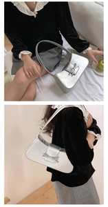 Close-up of silver baguette shoulder bag with metallic finish and bow detail