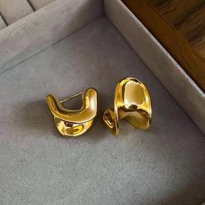 Detailed view of gold-plated irregular wave C-shape stud earrings in a velvet gift box