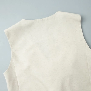 Close-up of linen vest neckline showing horizontal texture on light cream fabric