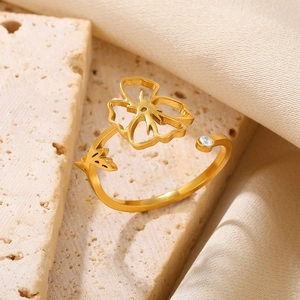 Detailed shot of a gold flower open ring with zircon on natural sandstone display
