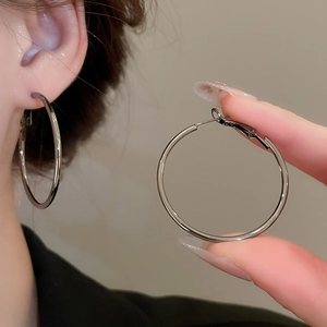 Close-up detail of oversized silver hoop earrings with a sleek minimalist metal finish