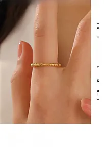 Dettaglio di un anello dorato a sfere con motivo a stella a otto punte su un dito