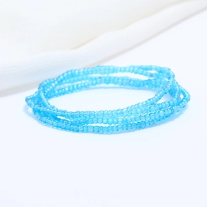 Detailed close-up of double-layered blue seed bead waist chain on soft white fabric