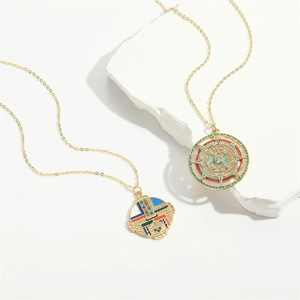 Vintage gold enamel heart and sun pendant necklaces displayed on a white textured stone