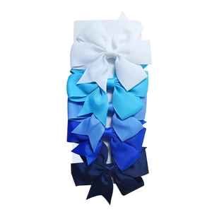 Close-up of five gradient blue ribbed ribbon bow hair clips stacked on a white display card