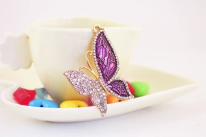 Close-up of golden butterfly keychain with purple enamel wings and sparkling rhinestones