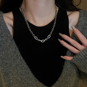 Macro detail of silver link chain necklace with sparkling zircon pavé on model's neck