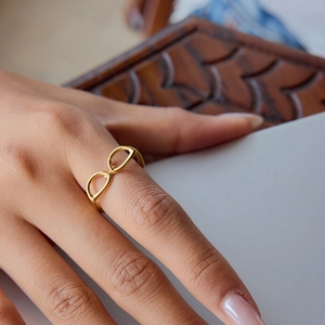 Close-up of golden infinity symbol ring on index finger with minimalist style