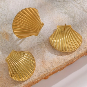 Detail view of golden shell earrings on natural stone surface with high-end texture