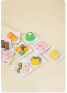 Macro view of assorted miniature food models and realistic dessert toys on white trays