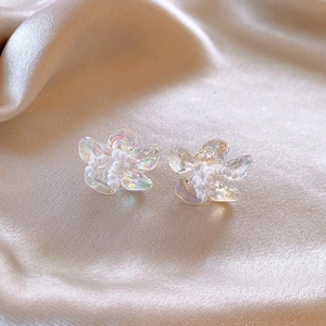 Close-up of elegant iridescent flower stud earrings on champagne silk background