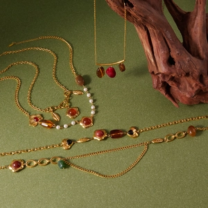 Artistic layout of gold resin necklaces with amber and green stones on green background