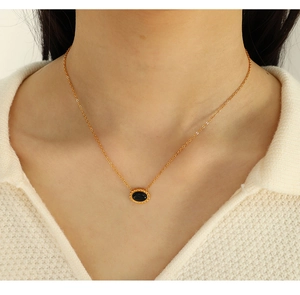 Detailed close-up of a gold necklace featuring an oval black tiger eye stone pendant