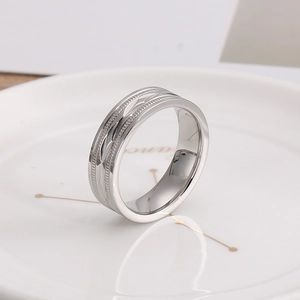 Macro detail of silver geometric wide ring with polished facets on white ceramic plate