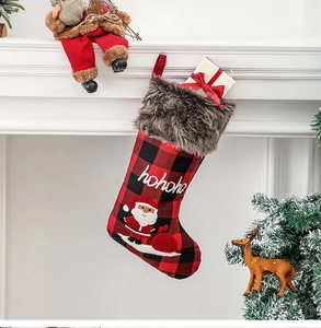Détail de chaussette de Noël à carreaux rouges et noirs brodée sur cheminée blanche